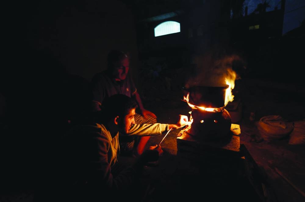 
Palestinians sit next to a fire near the rubble of a house hit in an Israeli strike during the conflict, amid a temporary truce between Hamas and Israel, in Khan Yunis in the southern Gaza Strip. 