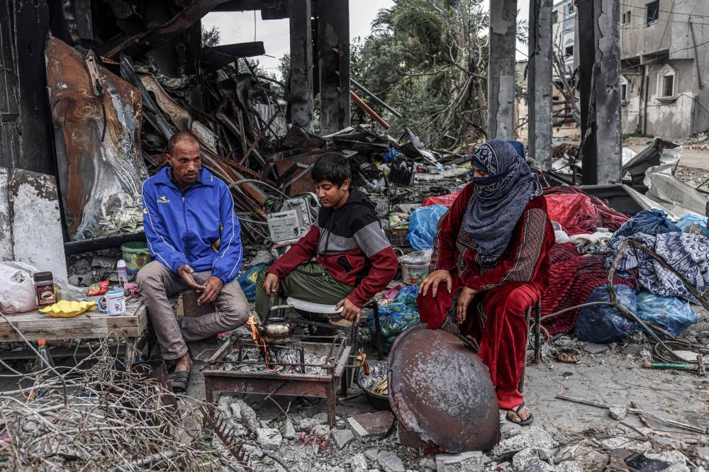 Palestinians cook outside amid the destruction caused by Israeli strikes in the village of Khuzaa, east of Khan Yunis near the border fence between Israel and the southern Gaza Strip, on Monday. AFP