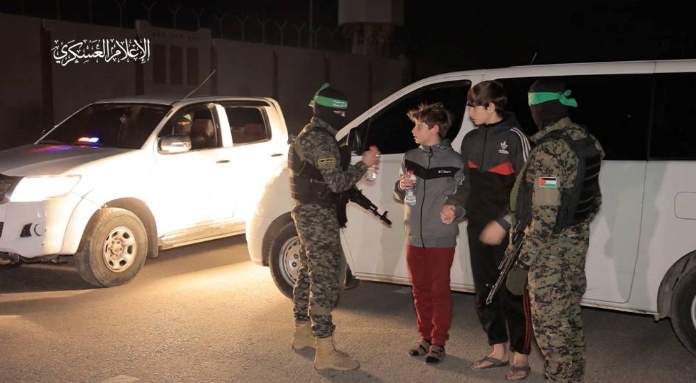 Hostages receive bottles of water as they are handed over by Hamas to members of the International Committee of the Red Cross at an unknown location in the Gaza Strip, Monday. Hamas Military Wing/Handout via REUTERS 