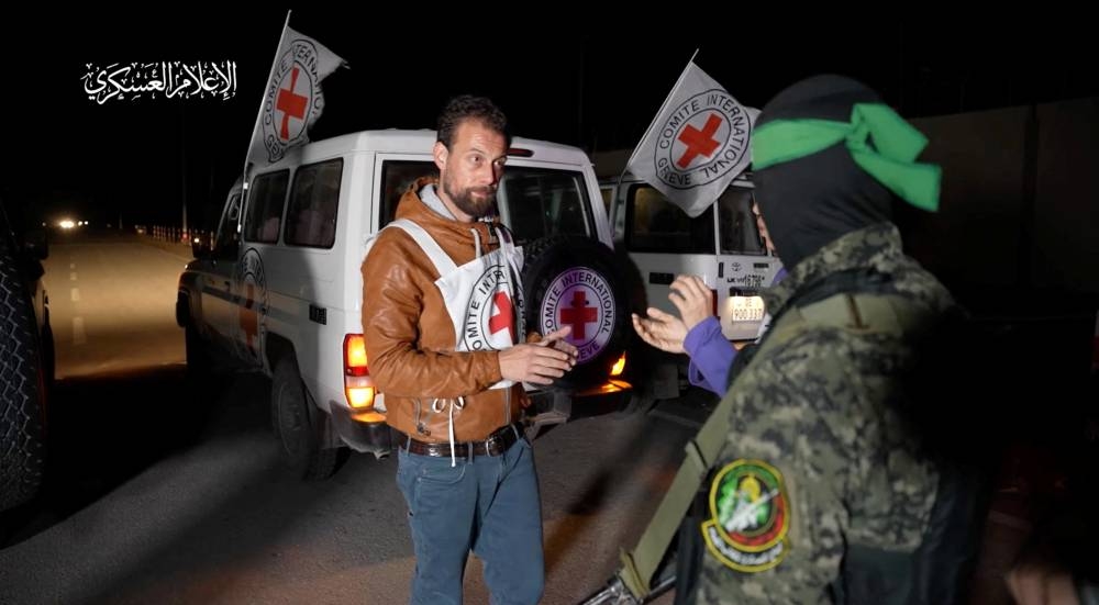 A Hamas fighter interacts with members of the International Committee of the Red Cross, as Hamas hand over hostages at an unknown location in the Gaza Strip, in this screen-grab taken from video released Monday. Hamas Military Wing/Handout via REUTERS