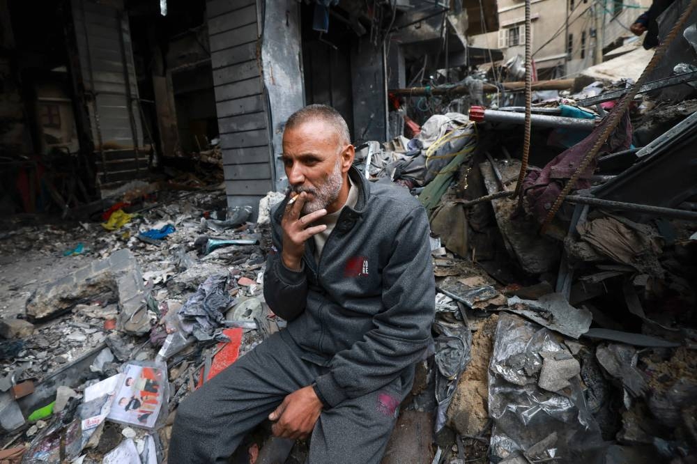 A Palestinian man smokes a cigarette amid the rubble in the southern Gaza Strip city of Khan Yunis on, on Tuesday. AFP