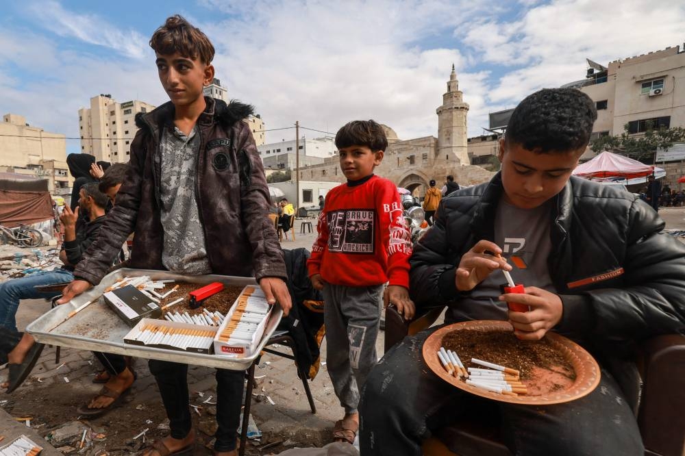 Palestinian youths sell cigarettes on a main square in the southern Gaza Strip city of Khan Yunis, on Tuesday. AFP