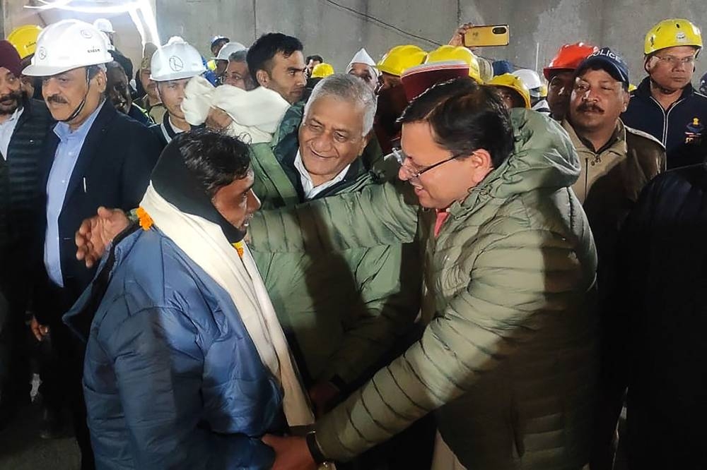 A contruction worker (front L) interacting with India's Minister of State of Road Transport and Highways VK Singh (C) and Chief minister of Uttarakhand Pushkar Singh Dhami (R) following his rescue from inside the under construction Silkyara tunnel during a rescue operation for trapped workers after a section of the tunnel collapsed in the Uttarkashi district of India's Uttarakhand state. AFP/  Department of Information and Public Relation, Uttarakhand