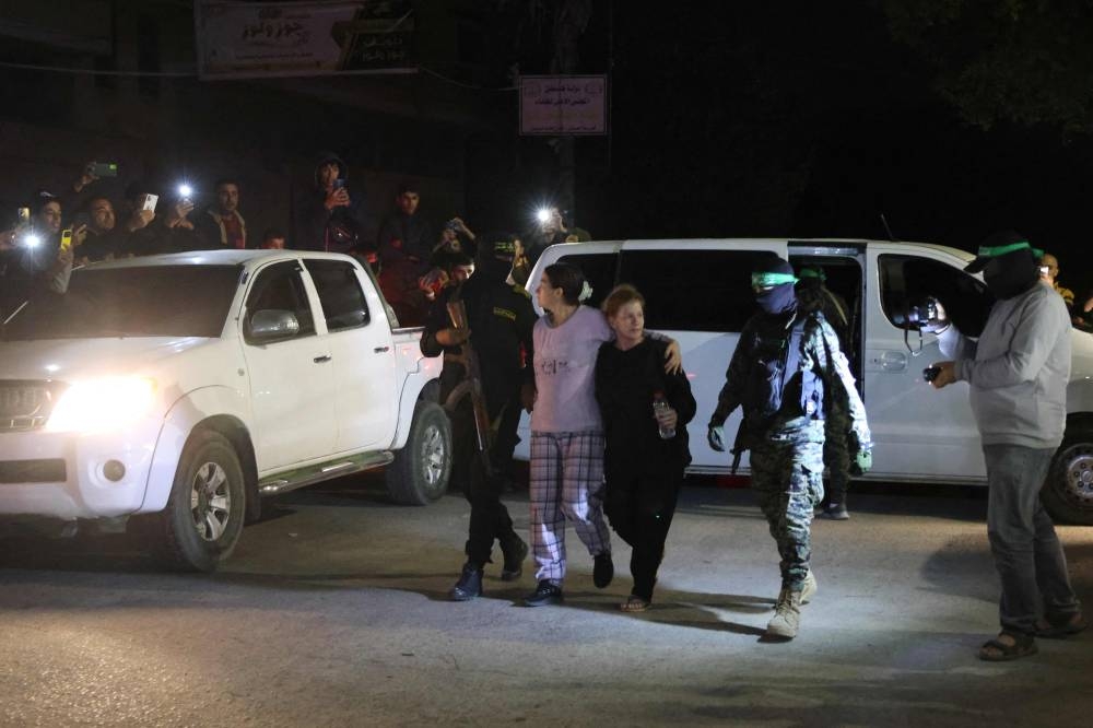Hamas fighters accompany newly released hostages before handing them over to the Red Cross in Rafah, in the southern Gaza Strip on Tuesday. REUTERS