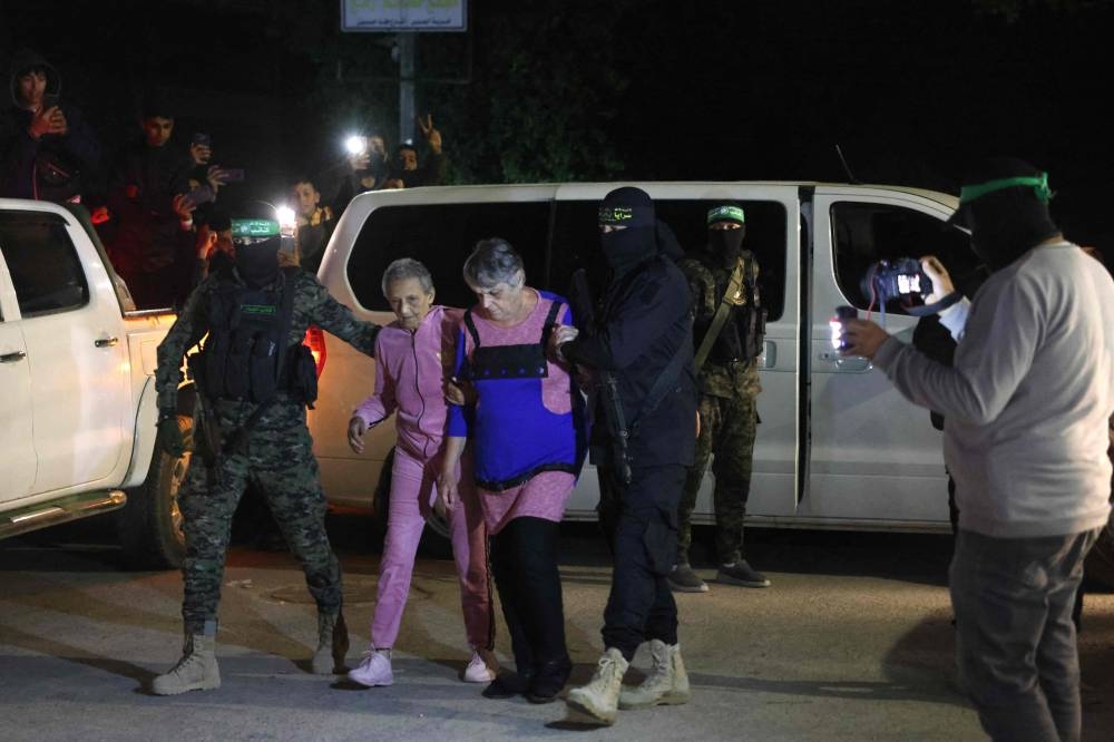 Hamas and Islamic Jihad fighters accompany newly released hostages before handing them over to the Red Cross in Rafah, in the southern Gaza Strip on Tuesday. AFP