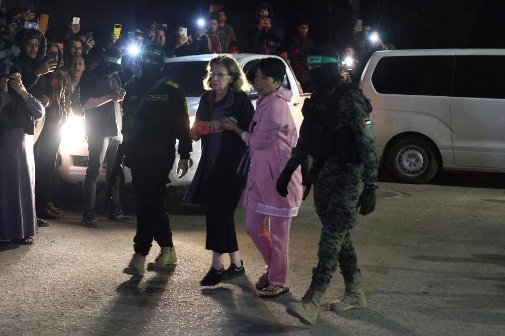 Hamas fighters accompany newly released hostages before handing them over to the Red Cross in Rafah, in the southern Gaza Strip on Tuesday. AFP