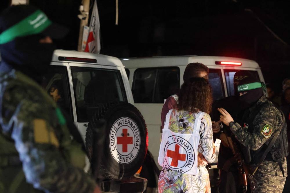 Hamas and Islamic Jihad fighters speak with members of the Red Cross during the release of hostages in Rafah, in the southern Gaza Strip on  Tuesday. AFP