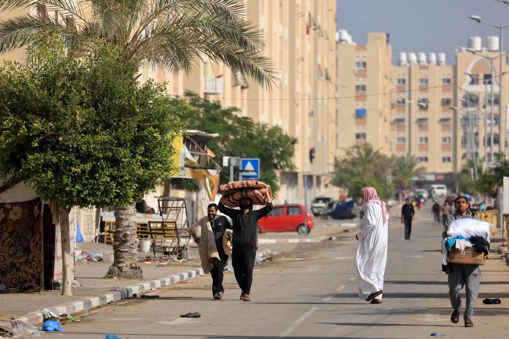 Residents of the Hamad Town residential complex in Khan Yunis in the southern Gaza Strip, carry some of their belongings as they flee their homes after receiving notification from the Israeli army of an imminent strike, on Saturday. AFP