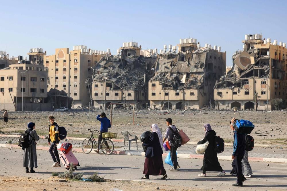 Residents of the Qatari-funded Hamad Town residential complex in Khan Yunis in the southern Gaza Strip, carry some of their belongings as they flee their homes after an Israeli strike, on Saturday. AFP
