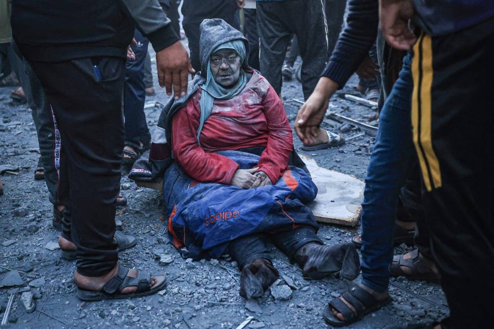 A woman injured in an Israeli strike sits amid the rubble in Rafah in the southern Gaza Strip on Sunday. AFP
