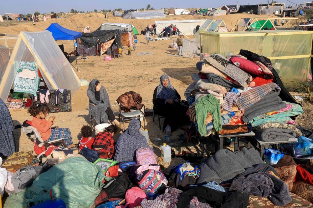 Displaced Palestinians who fled from Khan Yunis, sit with their belongings outside makeshift shelters in Rafah in the southern Gaza Strip on Monday. AFP