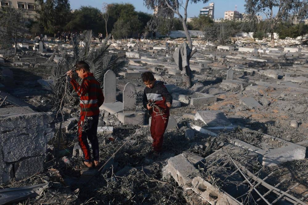 Palestinian boys collect wood near a cemetery damaged following Israeli air strikes in Rafah in the southern Gaza Strip early Monday. AFP