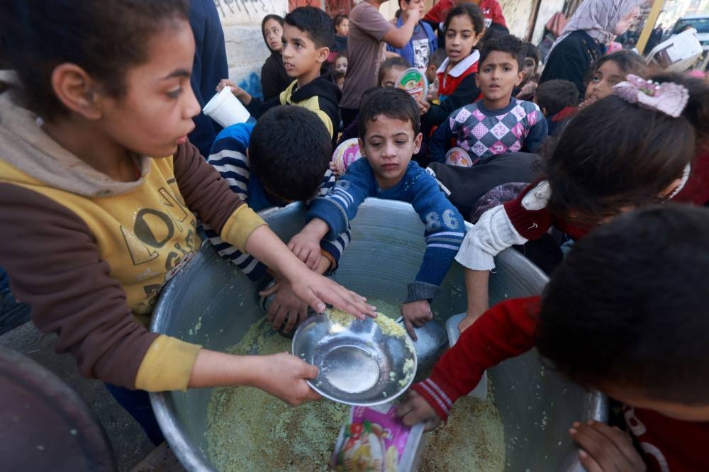 Palestinian children collect food at a donation point provided by a charity group in the southern Gaza Strip city of Rafah, on Wednesday. AFP