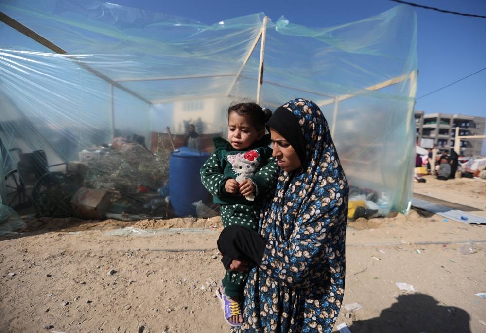 A woman holds a child as displaced Palestinians, who fled their houses due to Israeli strike, shelter in a camp in Rafah in the southern Gaza Strip, on Wednesday. REUTERS