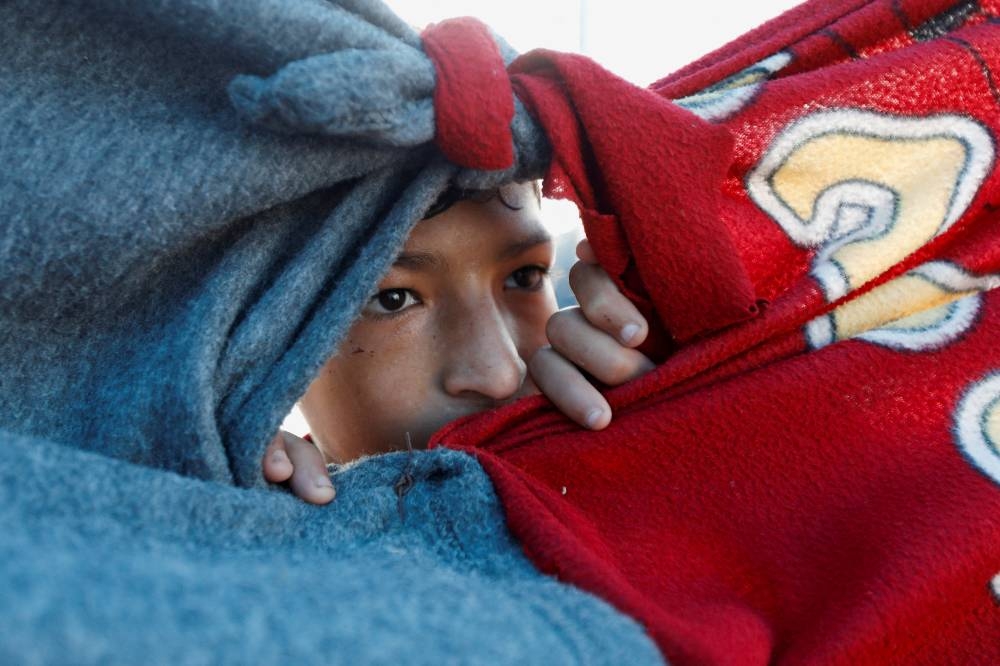A displaced Palestinian boy, who fled his family house due to Israeli strikes, looks through the cover of a tent at a camp sheltering displaced people, in Rafah, in the southern Gaza Strip , on Friday. REUTERS