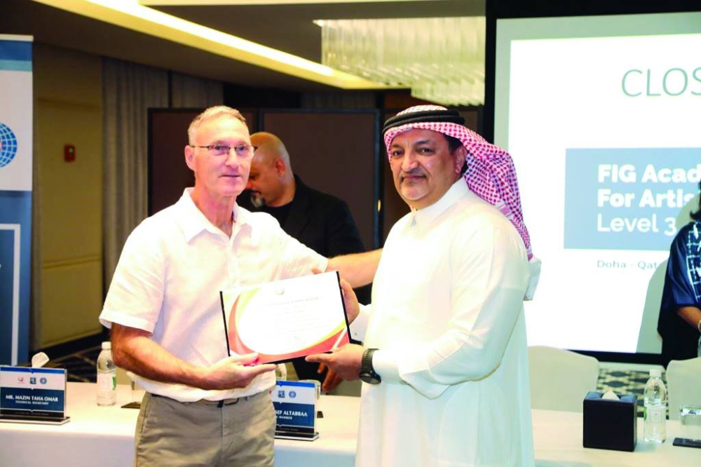 hands over a certificate at the end of the FIG Academy for Artistic Gymnastics Level III workshop for coaches that concluded in Doha.