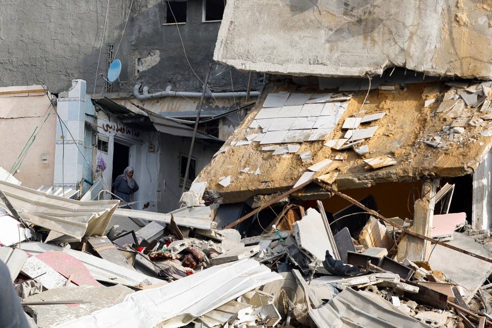 A Palestinian woman inspects the damage at the site of Israeli strikes on houses in Khan Younis in the southern Gaza Strip, on Tuesday. REUTERS