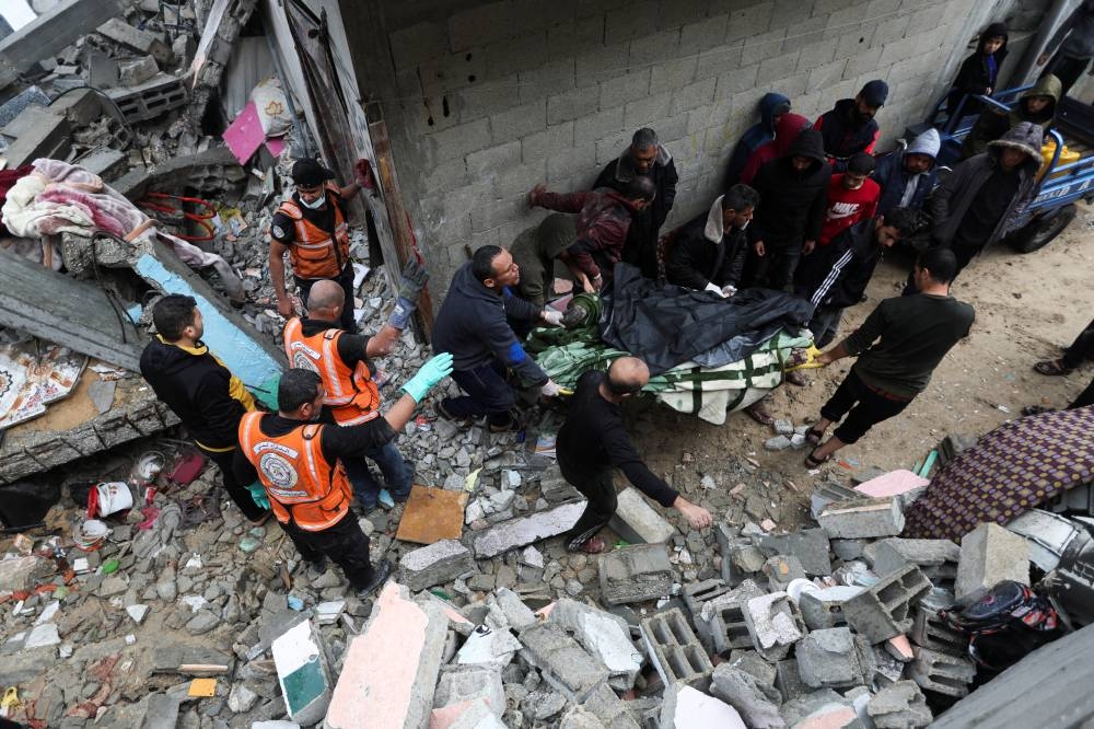 Palestinians carry a causality at the site of Israeli strikes on houses, in Khan Younis in the southern Gaza Strip, on Wednesday. REUTERS