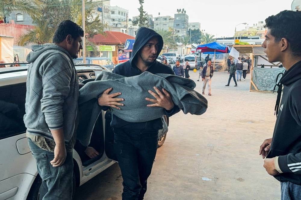 A Palestinian man carries a casualty while rushing into Nasser hospital, in Khan Younis, in the southern Gaza Strip, on Friday. REUTERS