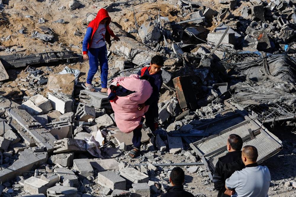 A Palestinian child carries items at the site of an Israeli strike on a house, in Rafah, in the southern Gaza Strip, on Saturday. REUTERS