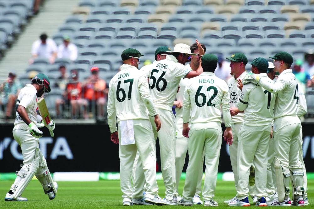 Australia’s players celebrate after taking the wicket of Pakistan’s Babar Azam (left) during day three of the first Test in Perth on Saturday. (AFP)