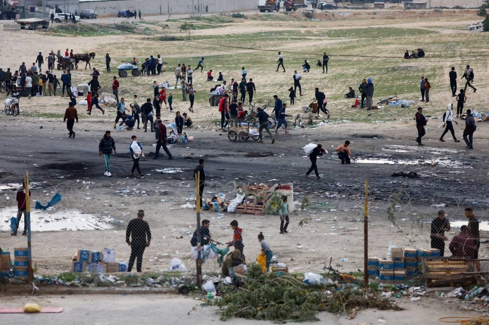 Palestinians gather to unload boxes with bottles of water from trucks at Rafah border with Egypt, in the southern Gaza Strip, on Sunday. REUTERS