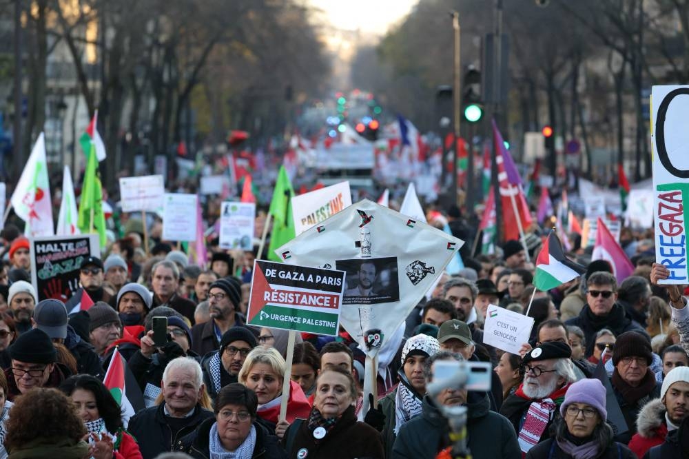 Protesters hold placards and flags during a rally calling for a permanent ceasefire in war between Israel and Hamas in Gaza, in Paris, on Sunday. AFP