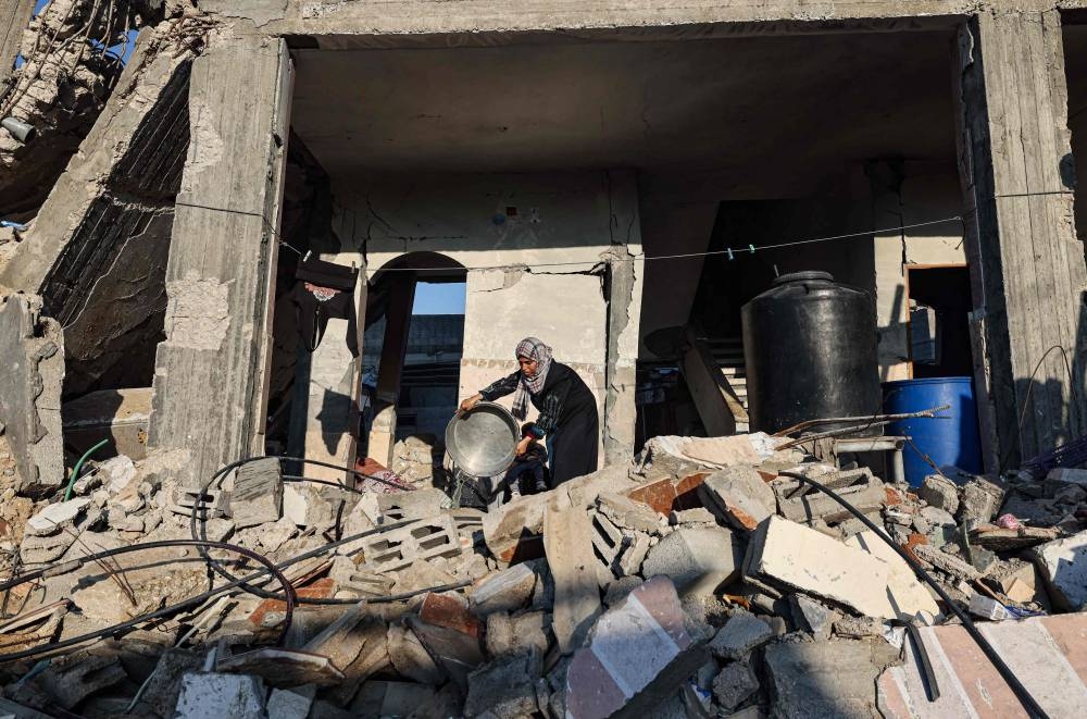 A woman throws used water as she washes clothes in her destroyed house in Rafah in the southern Gaza Strip on Monday. AFP