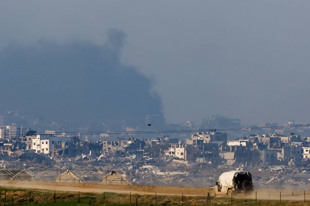 An Israeli military vehicle drives near damaged buildings in the Gaza Strip, as seen from southern Israel, on Tuesday. REUTERS