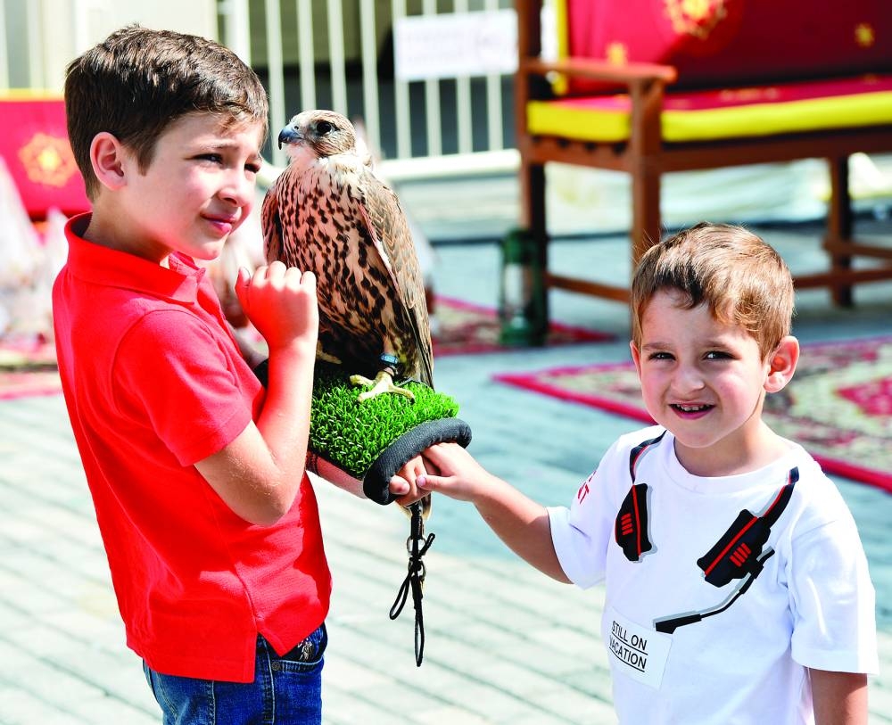 Young visitors pose with a falcon resting on their forearm. PICTURE: Shaji Kayamkulam