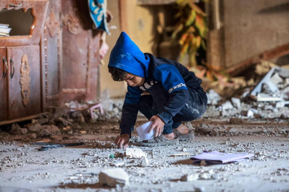 A Palestinian boy collects small pieces of debris following Israeli bombardment in Rafah in the southern Gaza Strip, on Friday. AFP