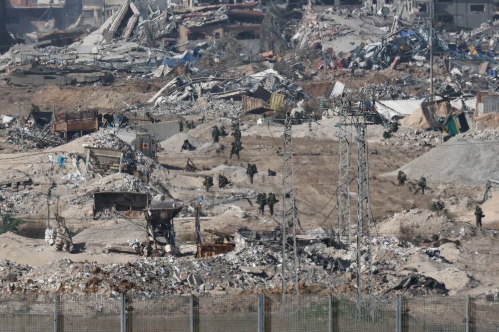 Israeli soldiers walk among the debris in Gaza as seen from Israel, on Friday. REUTERS