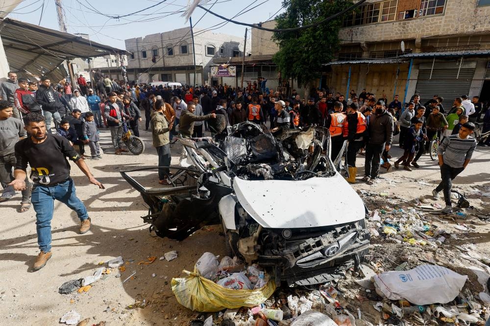 Palestinians inspect the site of an Israeli strike on a car in Rafah, southern Gaza Strip, on Friday. REUTERS