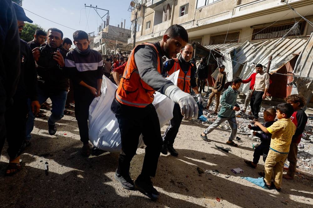 Palestinians carry a casualty near the site of an Israeli strike on a car, on Friday. REUTERS