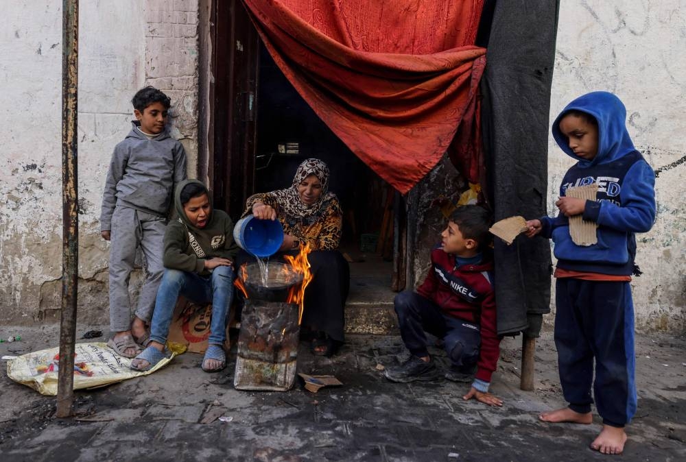A Palestinian woman makes food outside a house in the southern Gaza Strip, on Friday. AFP