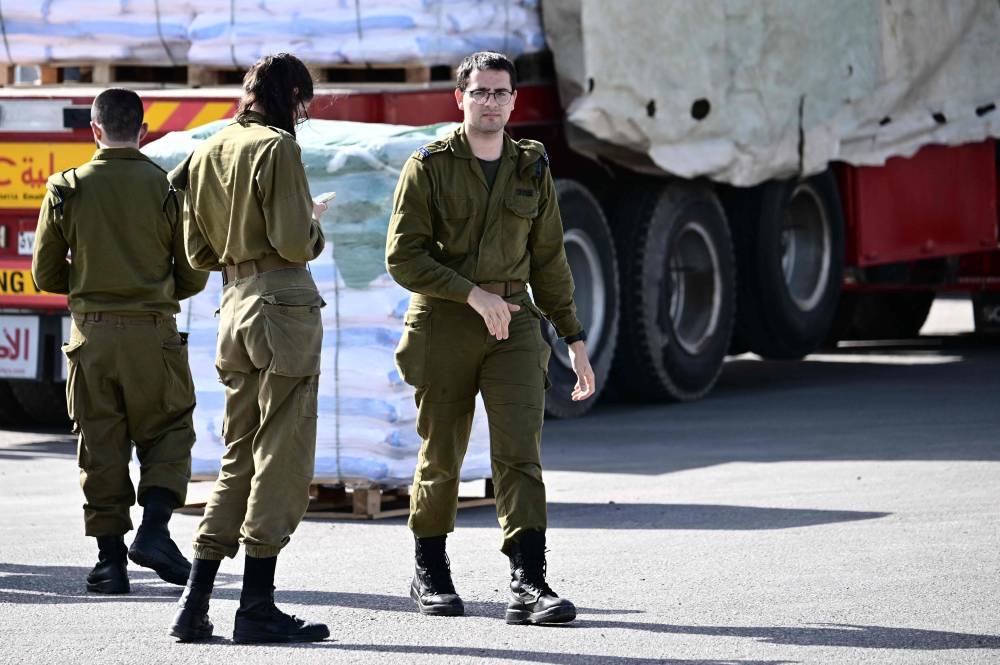 Members of Israeli security forces inspect humanitarian aid trucks arriving from Egypt on the Israeli side of the Kerem Shalom border crossing with the southern Gaza Strip, on Friday. AFP