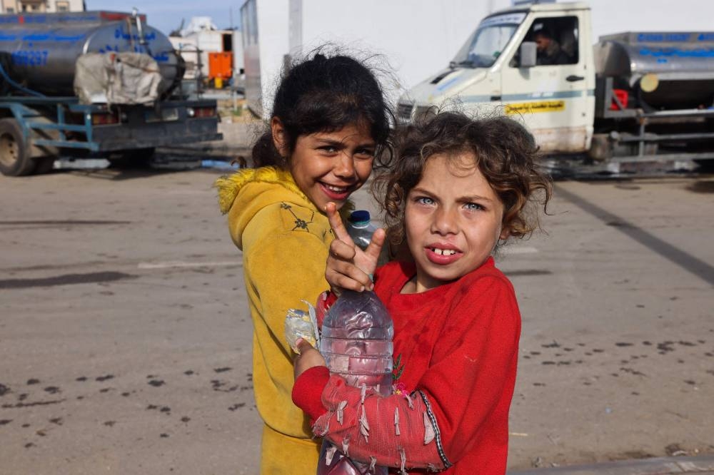 Displaced Palestinian girls carry water bottles near at a makeshift shelter area in Rafah in the southern Gaza Strip on, on Sunday. AFP
