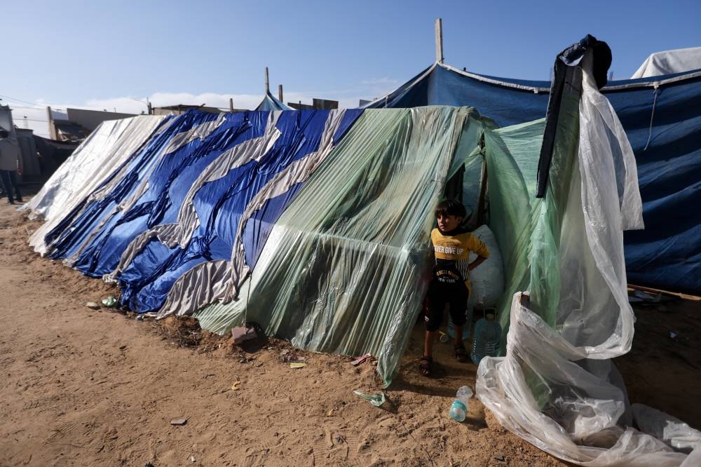 A Palestinian boy stands near a makeshift tent, as displaced Palestinians, who fled their houses due to Israeli strikes, shelter in a tent camp, in Rafah in the southern Gaza Strip, on Sunday. REUTERS