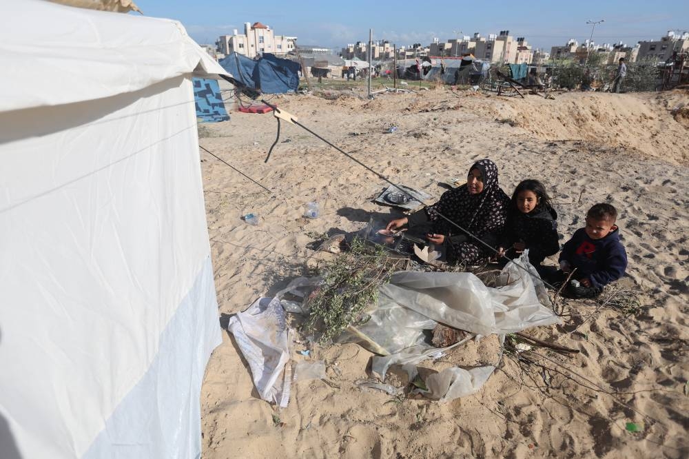 Displaced Palestinian woman and children, who fled their house due to Israeli strikes, shelter in a tent camp in Rafah in the southern Gaza Strip, on Sunday. REUTERS