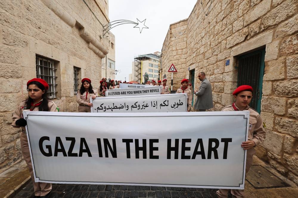 Scouts hold a sign in solidarity with Palestinians in Gaza, on the day of a visit by the Latin Patriarch of Jerusalem, Pierbattista Pizzaballa to the Old City of Bethlehem for Christmas events, in the Israeli-occupied West Bank, on SUnday. REUTERS