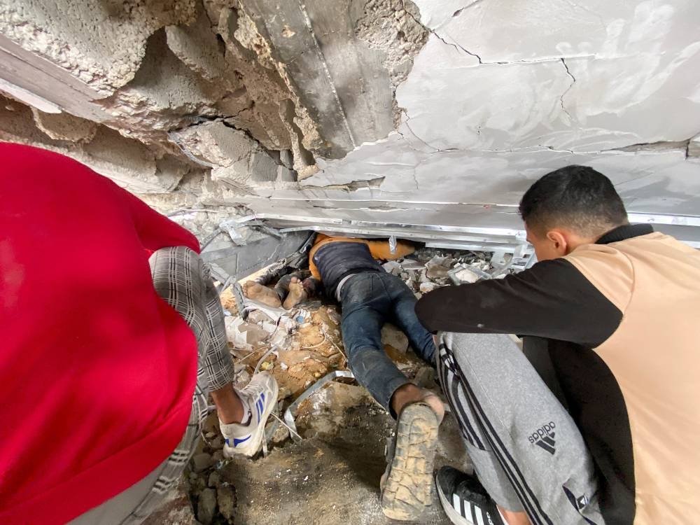 Palestinians work to remove the body of a relative, who was killed in an Israeli air strike, from under the rubble, at the Maghazi camp, in the central Gaza Strip, on Monday. REUTERS