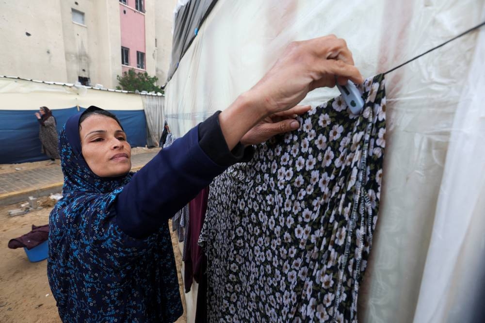 A woman hangs washing as displaced Palestinians, who fled their houses due to Israeli strikes, shelter in a tent camp, in Rafah in the southern Gaza Strip, on Monday. REUTERS