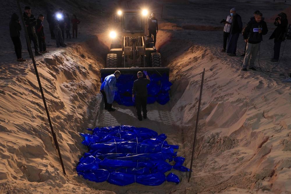 The shrouded bodies of Palestinians killed in northern Gaza, that were taken and later released by Israel, are buried in a mass grave in Rafah, on the southern Gaza Strip on, on Tuesday. AFP