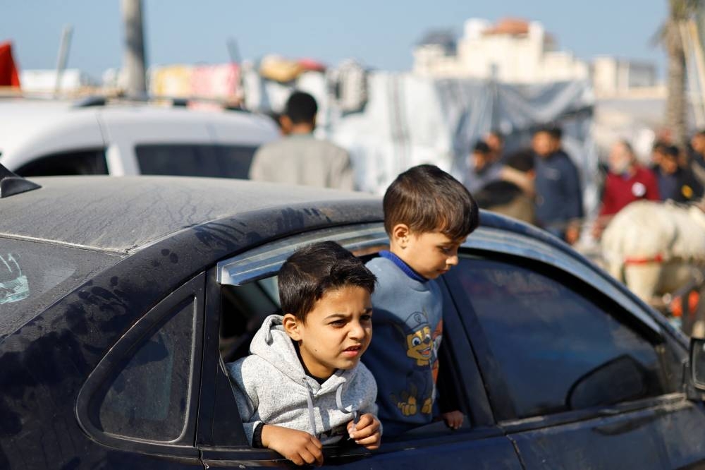 Displaced Palestinian children, part of a group who fled their homes due to Israeli strikes, look out from a car, at a tent camp, in Rafah, southern Gaza Strip, on Friday. REUTERS