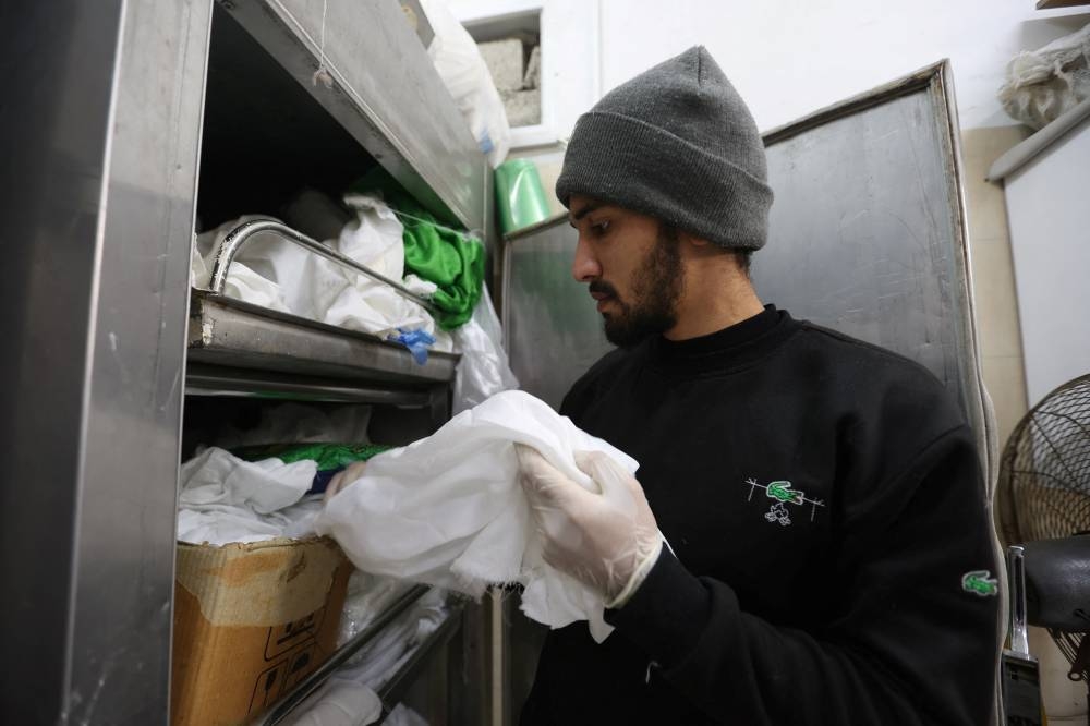 A volunteer at Keratan society which prepares dead bodies for burial, prepares a white shroud, at a hospital in Rafah, southern Gaza Strip, on Friday. REUTERS