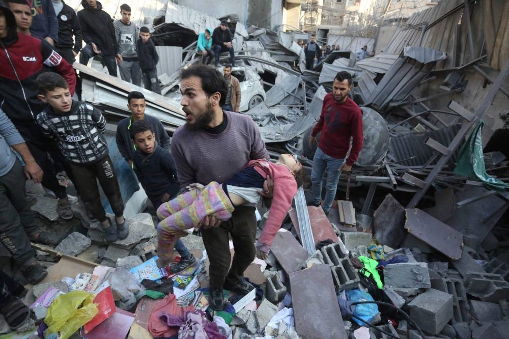  Palestinian man carries the body of a child after it was unearthed from the rubble of a building following an Israeli strike on the Zawayda area of the central Gaza Strip on Saturday. AFP