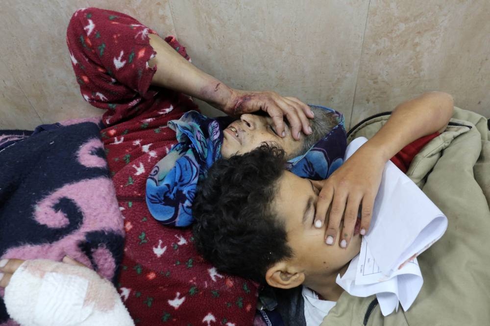 A woman and a child injured in an Israeli bombardment lie side by side at the emergency ward of the al-Aqsa hospital in Deir al-Balah in the central Gaza Strip on Saturday. AFP