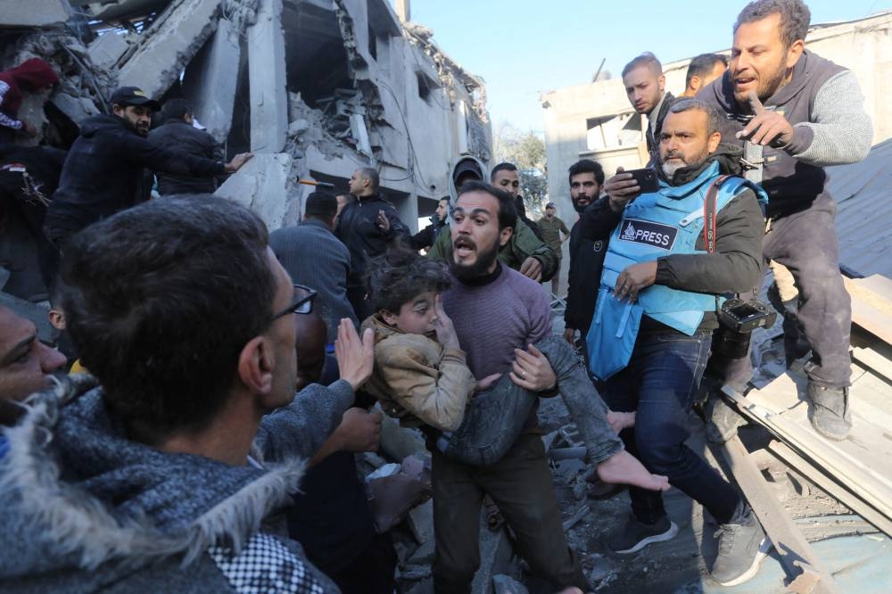 A Palestinian man evacuates a wounded girl from the site of an Israeli strikes on the Zawayda area of the central Gaza Strip Saturday.