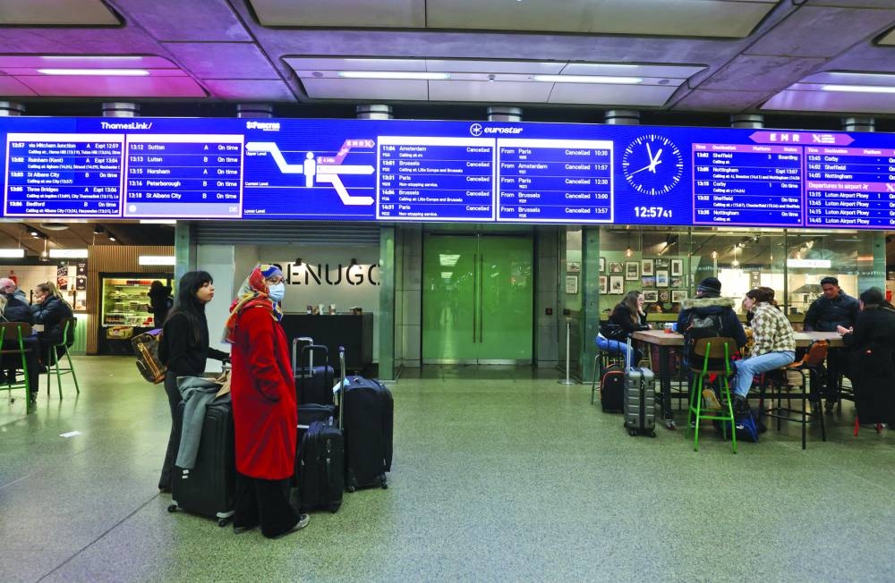 
Passengers wait as a board shows cancelled trains at St Pancras International Station after the services are cancelled due to a flooded tunnel, in London. 