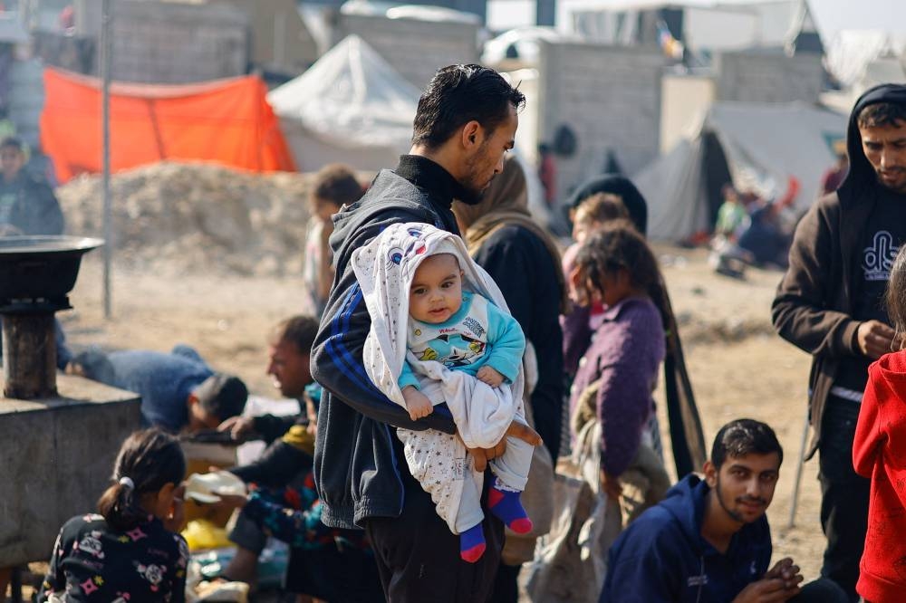 A man holds a baby as displaced Palestinians, who fled their homes due to Israeli strikes, shelter in a tent camp, in Rafah, southern Gaza Strip, on Monday. REUTERS
